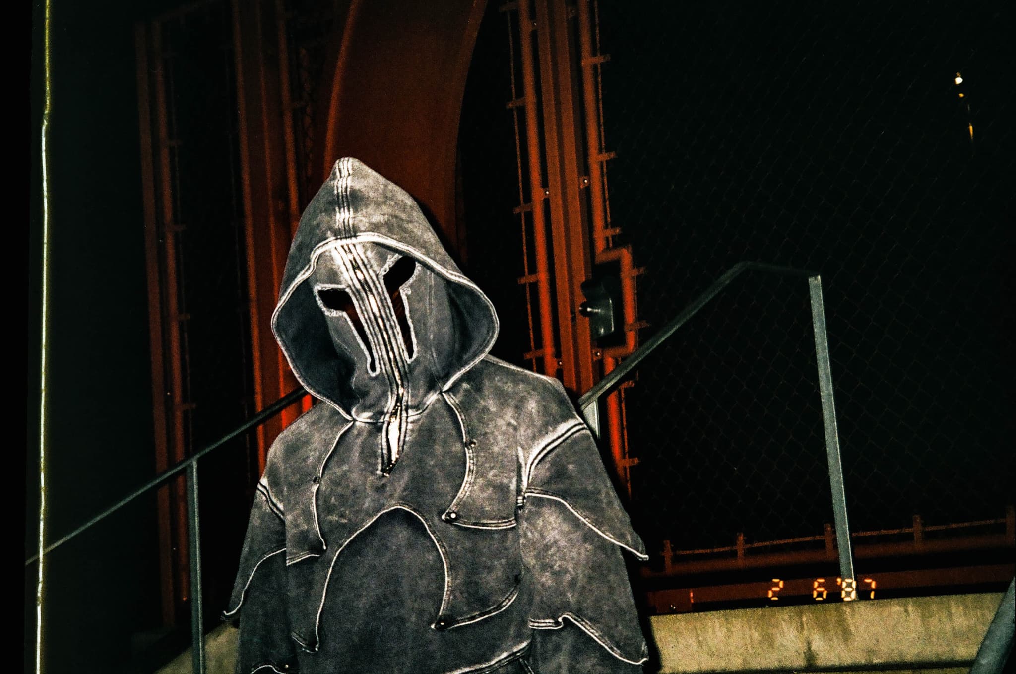 DRACU in the hooded mask, shot on film beneath a steel structure
